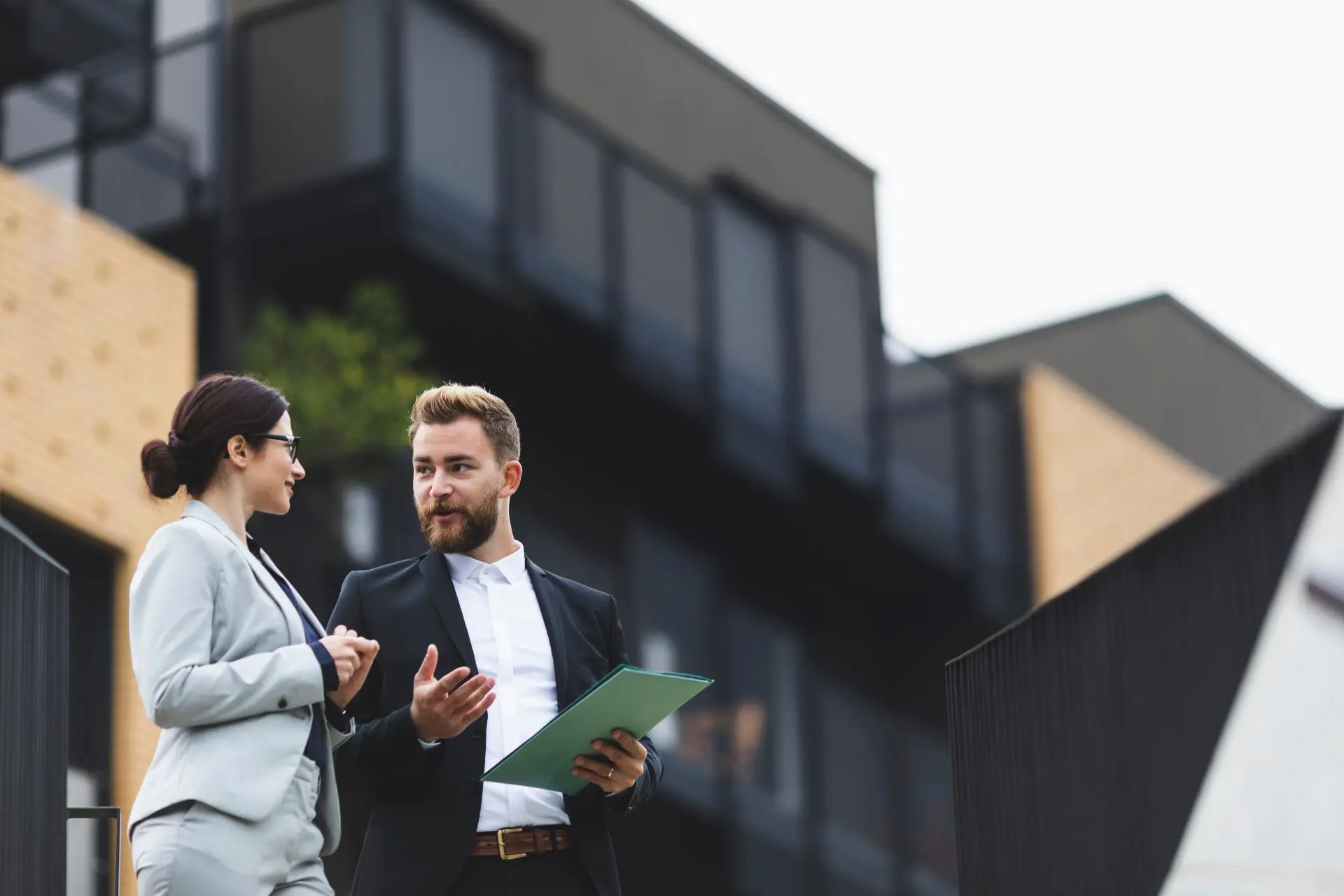 Business professionals discussing client matters outside a modern office building