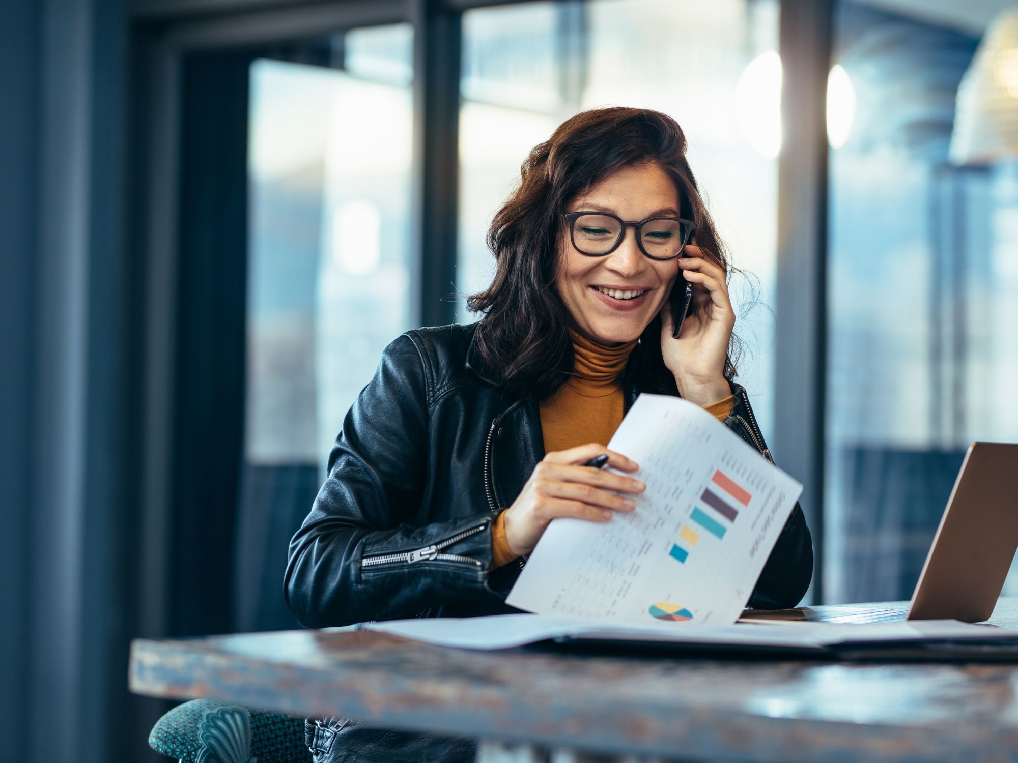 Business professional reviewing documents while handling phone communication