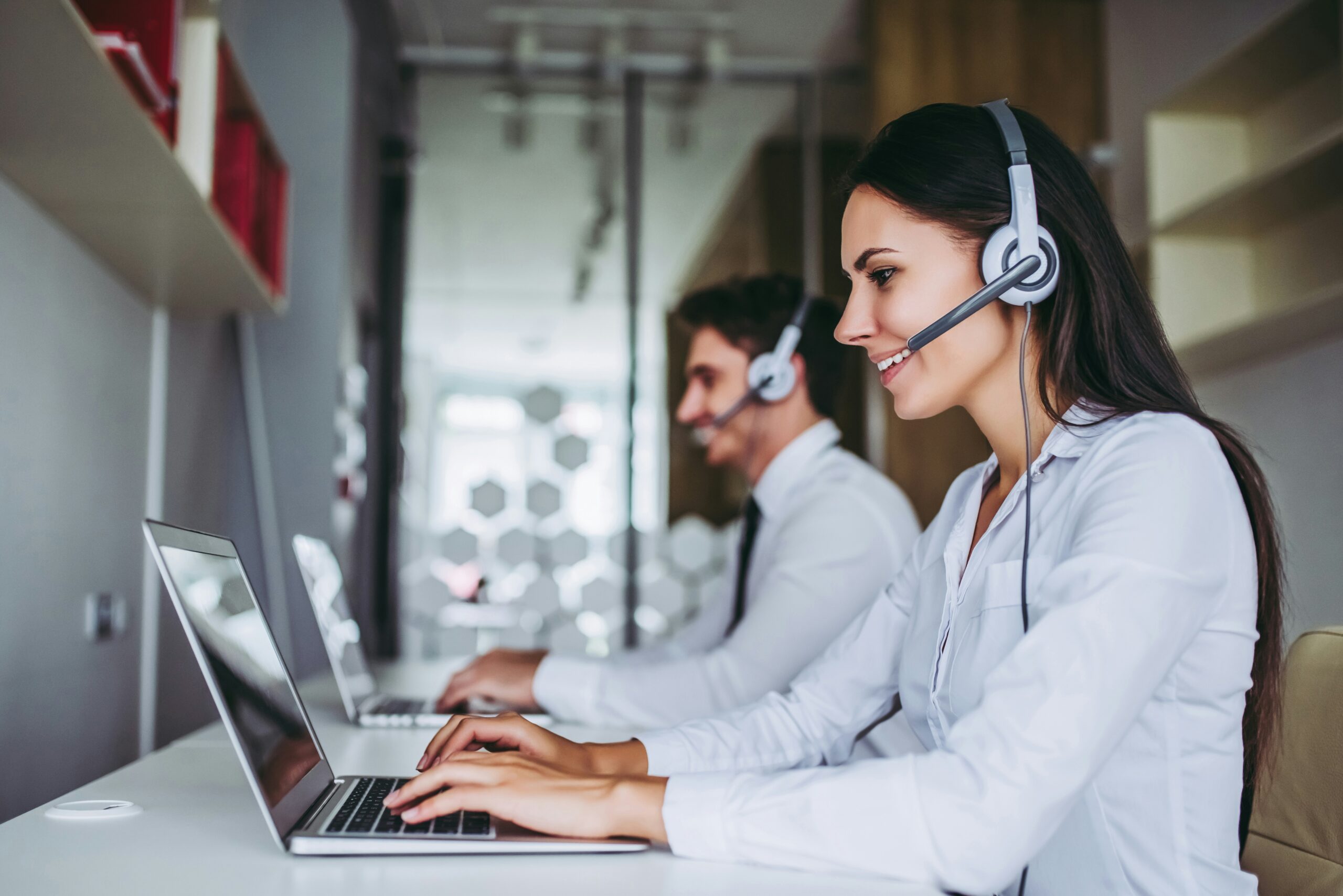 Professional agents wearing headsets and working on laptops, representing a live answering service for small businesses.